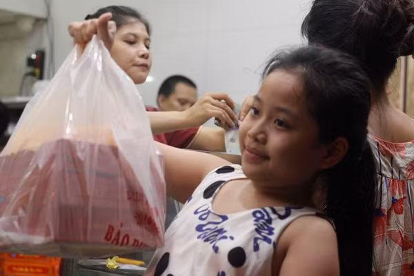 Em nhỏ vui mừng khoe túi bánh Trung thu vừa mua được sau quãng thời gian xếp hàng cùng người thân chờ đợi.