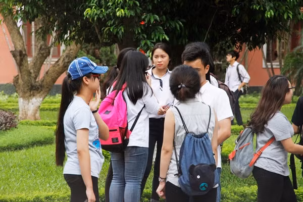 Nhiều thí sinh tranh thủ nán lại sân trường để cùng nhau nhìn lại đề thi vì làm bài không thật sự tự tin. Ảnh: Mạnh Hưng.