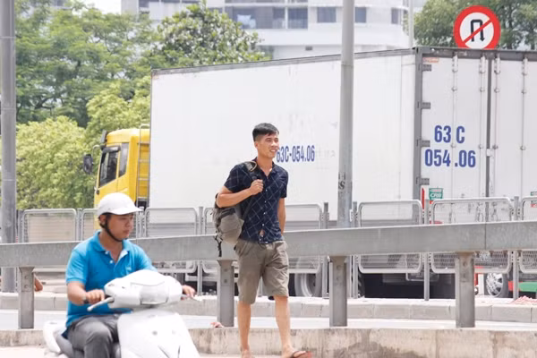 Nam thanh niên tỏ ra sốt ruột khi phải liên tục đi lại vì đứng lâu dưới nắng nóng đợi xe ở ngay đầu đường cao tốc trên cao.