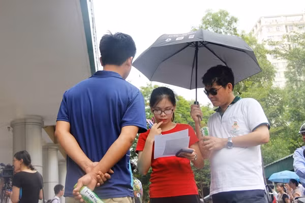 Em Hoàng Thảo Anh có chút lo lắng cho bài làm khi được người thân hỏi han, em vẫn nán lại trường thi để xem lại các câu hỏi. Ảnh: Mạnh Hưng.