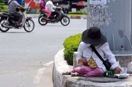 Người bán vé số đoạn Ngã tư Hàng Xanh, quận Bình Thạnh nấp phía sao cột điện cao thế để trốn nắng.