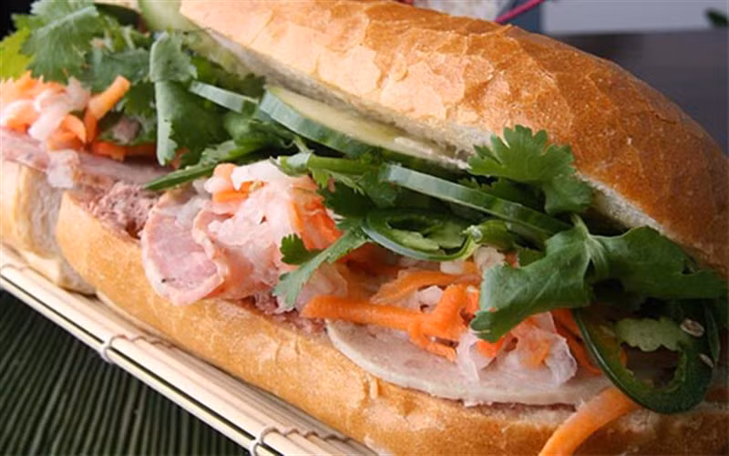 Dưa leo rửa sạch, bỏ cuốn, cắt khoanh mỏng. Ngò rí nhặt sạch, rửa sạch. Ớt rửa sạch, cắt khoanh nhỏ. Chả lụa cắt lát mỏng. Cắt đôi 1 bên bánh mì rồi phết đều muối tiêu vào mặt trong. Sau đó nhồi lần lượt chả lụa, cà rốt, củ cải trắng, dưa leo, ớt, ngò rí vào là có thể dùng được. Ảnh: cooky.vn.