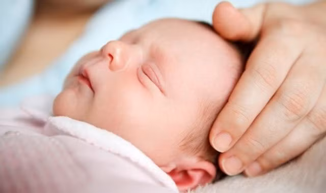 Mẹ không nên đặt bé nằm nhiều để tránh bị bẹp đầu, chăm xoa đầu bé để bé có đầu tròn trịa. Ảnh: mayduavong.mobi.