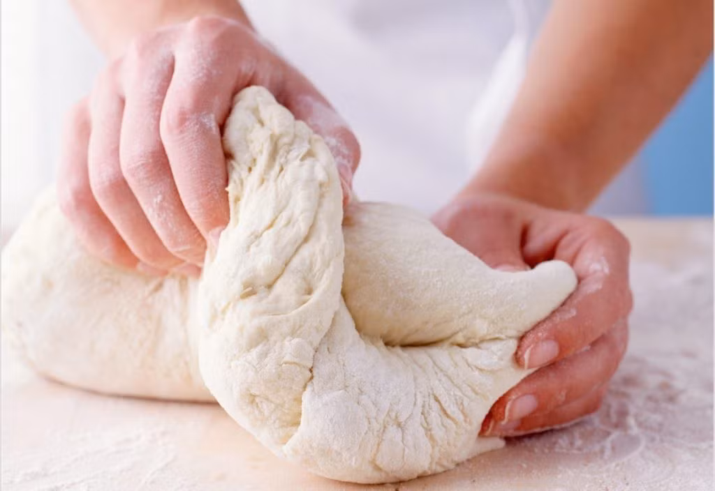 Nêm nếm sao cho vừa khẩu vị. Cho nước ấm và đường vào tô, hòa tan lại. Nêm đường. Thêm bột nở vào khuấy tan, để yên gần 10 phút cho đến khi thấy men nổi trên mặt nước là đạt. Nêm vào một ít muối dằn vị vào bột mì và cho thêm nước men pha đường trên vào nhồi bột mì. Ảnh: botducthinh.com.