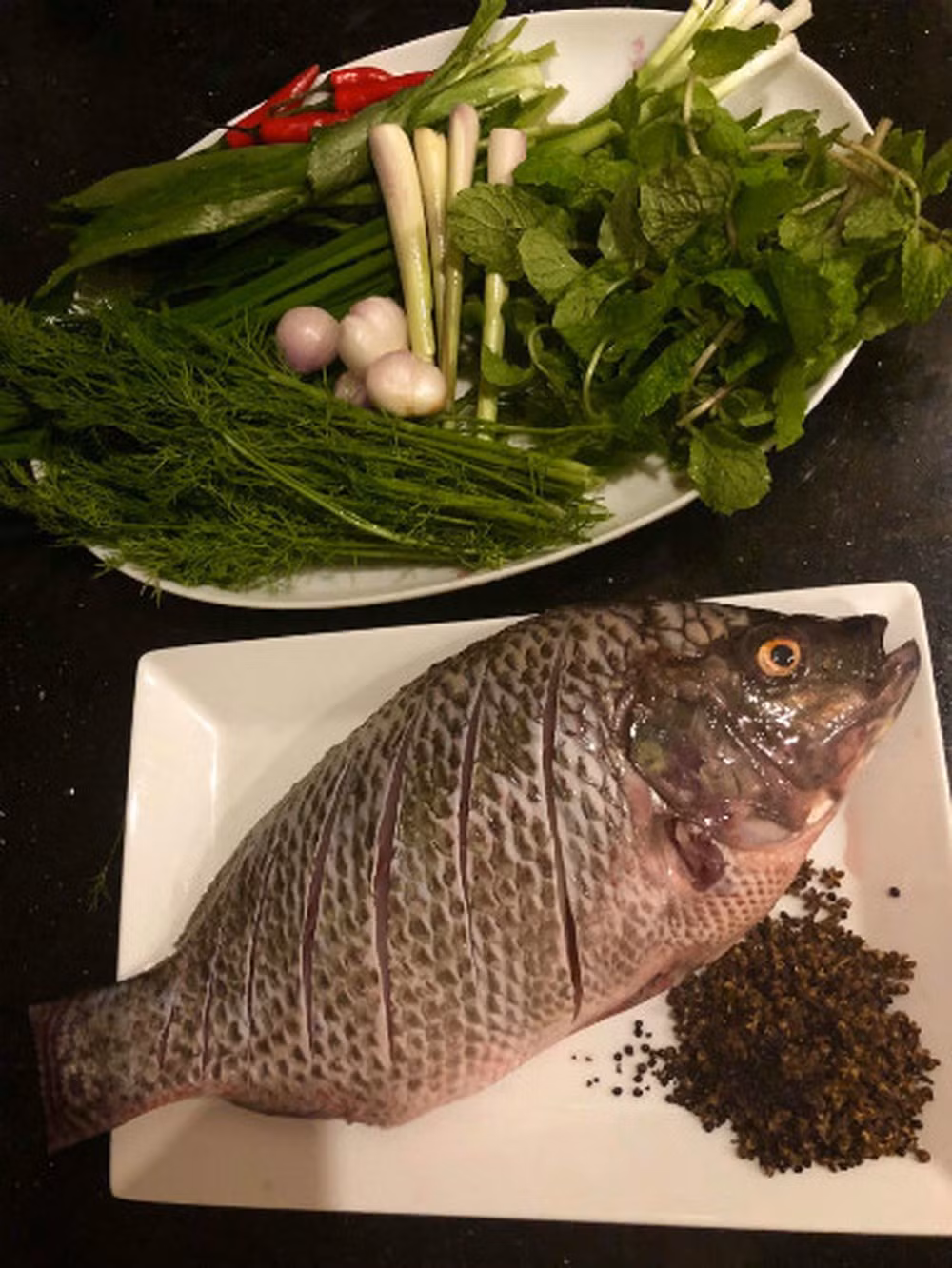 1. Cá nướng mắc khén. Nguyên liệu: Cá rô phi, mắc khén rang chín, giã nhỏ, hạt dổi, hành khô, sả, thì là, húng quế, ngổ, mùi tàu, ớt tươi, riềng, hành lá. Cá rửa sạch, khía hai bên mặt ngoài. Nên mổ cá từ lưng để khi nhồi rau nướng sẽ không bị rớt ra ngoài. Các loại rau rửa sạch để ráo nước.