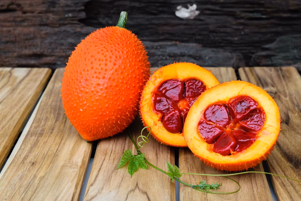 2. Bánh gấc: Bột nếp nước, đậu xanh, mỡ phần, mứt bí, hạt sen, dừa sợi, gấc, mè trắng, đường, vani, dầu ăn, lá chuối. Gấc bổ đôi, moi lấy hạt, trộn đều với ít rượu trắng cho ra phần thịt đỏ, bóc bỏ hạt gấc. Ảnh: HelloBacsi.com.