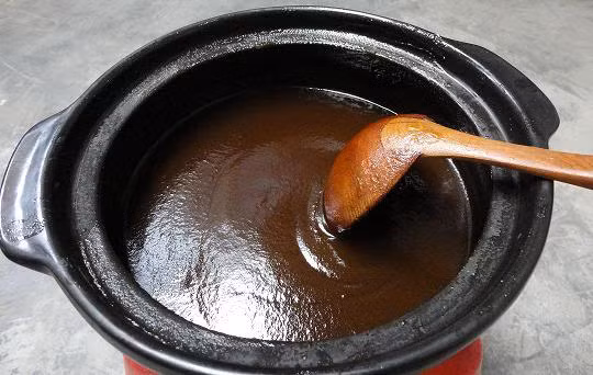 Đun bí trên bếp lửa nhỏ, không cho thêm chút nước nào, tự bí sẽ chảy ra nước. Khi nồi bí sôi thì bạn cho lửa nhỏ nhất có thể, hầm bí trong khoảng 2 tiếng, cho tới khi dùng muôi ấn thấy bí nát nhừ, nước bí nâu và sánh.