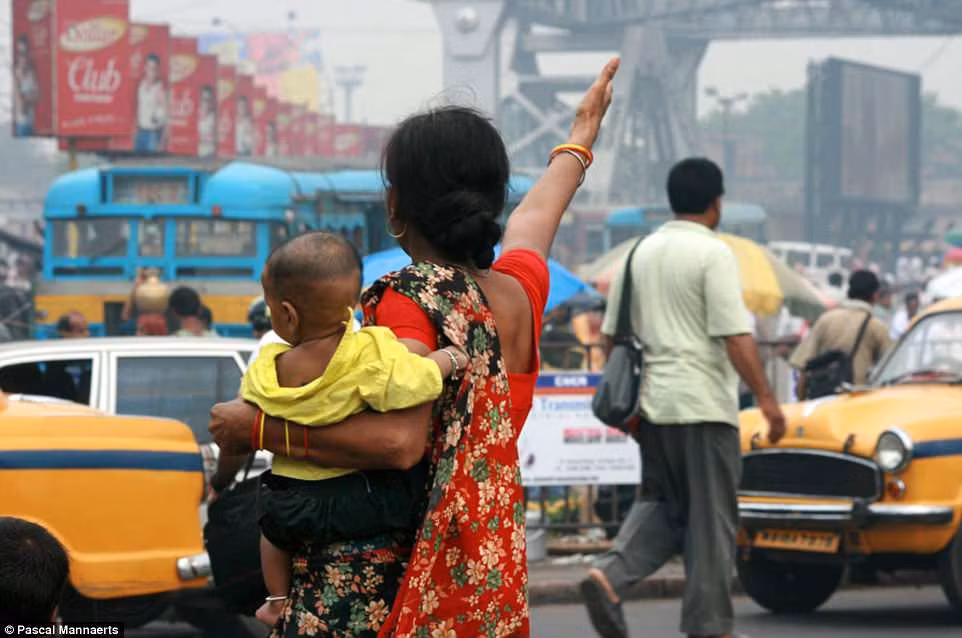 Một bà mẹ bế con khi tham gia giao thông ở Kolkata, Ấn Độ năm 2013.