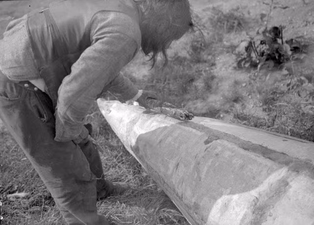 Người đàn ông đang sửa chữa vết nứt trên chiếc ca nô ở Bắc Saskatchewan hồi thập niên 1930. Ảnh: VT.