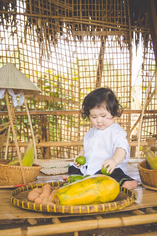 Mới đây, bé gái chưa đầy một tuổi này lại khiến người hâm mộ một phen “cười ngả nghiêng” khi hóa thân thành cô nông dân nhí múp míp, tạo dáng đáng yêu bên vườn tược.