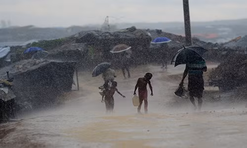 Bé trai Rohingya xách nước dưới trời mưa tầm tá tại khu trại tị nạn Kutupalong ở huyện Ukhia, Bangladesh, ngày 12/10/2017. Ảnh: The Atlantic.