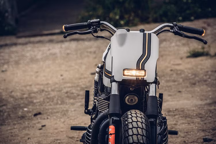 Việc "biến hình" Triumph Thruxton từ một mẫu xe môtô cafe racer để trở thành flat tracker bắt đầu bằng cách lột bỏ hoàn toàn đèn pha nguyên bản của xe, thay vào đó là một tấm chắn ở phía trước theo đúng phong cách, kèm theo đèn pha LED "siêu gọn". Trong khi đó, đèn xi-nhan của xe được Chun sử dụng loại gắn gù của Motogadget.