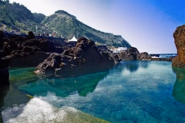7. Hồ dung nham tự nhiên ở Porto Moniz Porto Moniz là một ngôi làng trong khu nghỉ dưỡng nổi tiếng của Madeira, nằm ở Đại Tây Dương thuộc quần đảo Bồ Đào Nha. Một trong những nơi hấp dẫn nhất của điểm du lịch nổi tiếng này là khu vực tập trung các hồ nước vô tận tự nhiên, được tạo nên bởi những tảng đá dung nham sừng sững đen kịt mang hình thù kỳ lạ, ngập trong nước thủy triều trong vắt. Đắm mình trong làn nước yên ả, tách biệt với biển thét gào xung quanh quả là một trải nghiệm khó quên dành cho du khách.