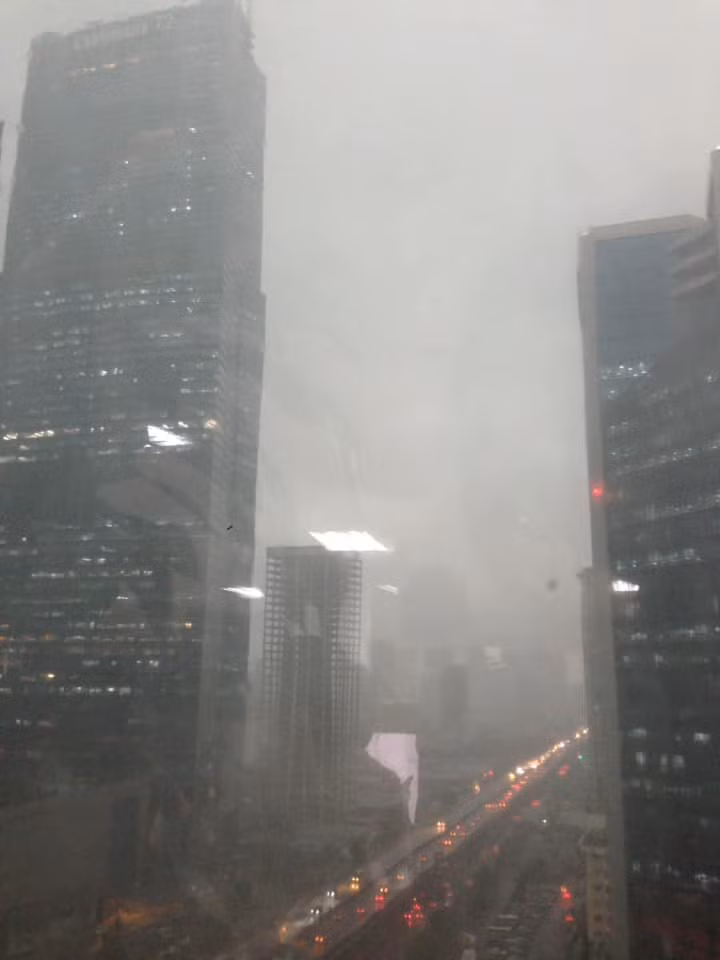 Dù mới 14h chiều (20/8), trời đang quang - sáng bỗng dưng tối sầm. Đến 14h30, mưa lớn bắt đầu trút xuống. Người lưu thông trên đường đều phải bật đèn pha, các cửa hàng, văn phòng cũng đua nhau sáng điện. (Ảnh PLO) 