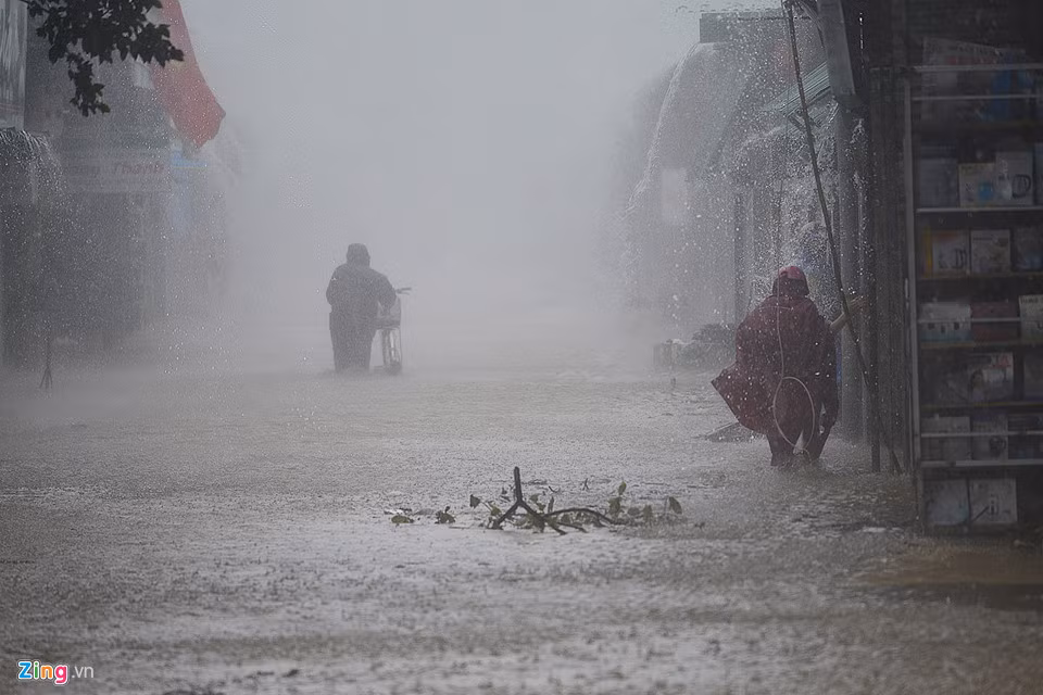 Nước càng lúc càng ngập sâu, tấn công nhà dân hai bên đường. Ảnh: Lê Hiếu.