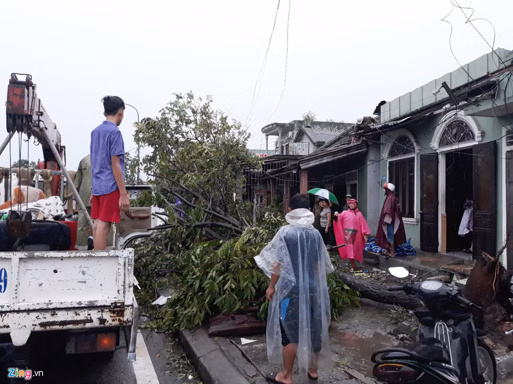Các cây đổ kịp thời được cơ quan chức năng điều xe cẩu tới thu dọn và đưa đi nơi khác. Theo thống kê, hơn 500 ngôi nhà ở thị xã Hương Thủy (Thừa Thiên - Huế) bị tốc mái và hàng trăm cây lớn bật gốc. Ảnh: Điền Bá Quang.