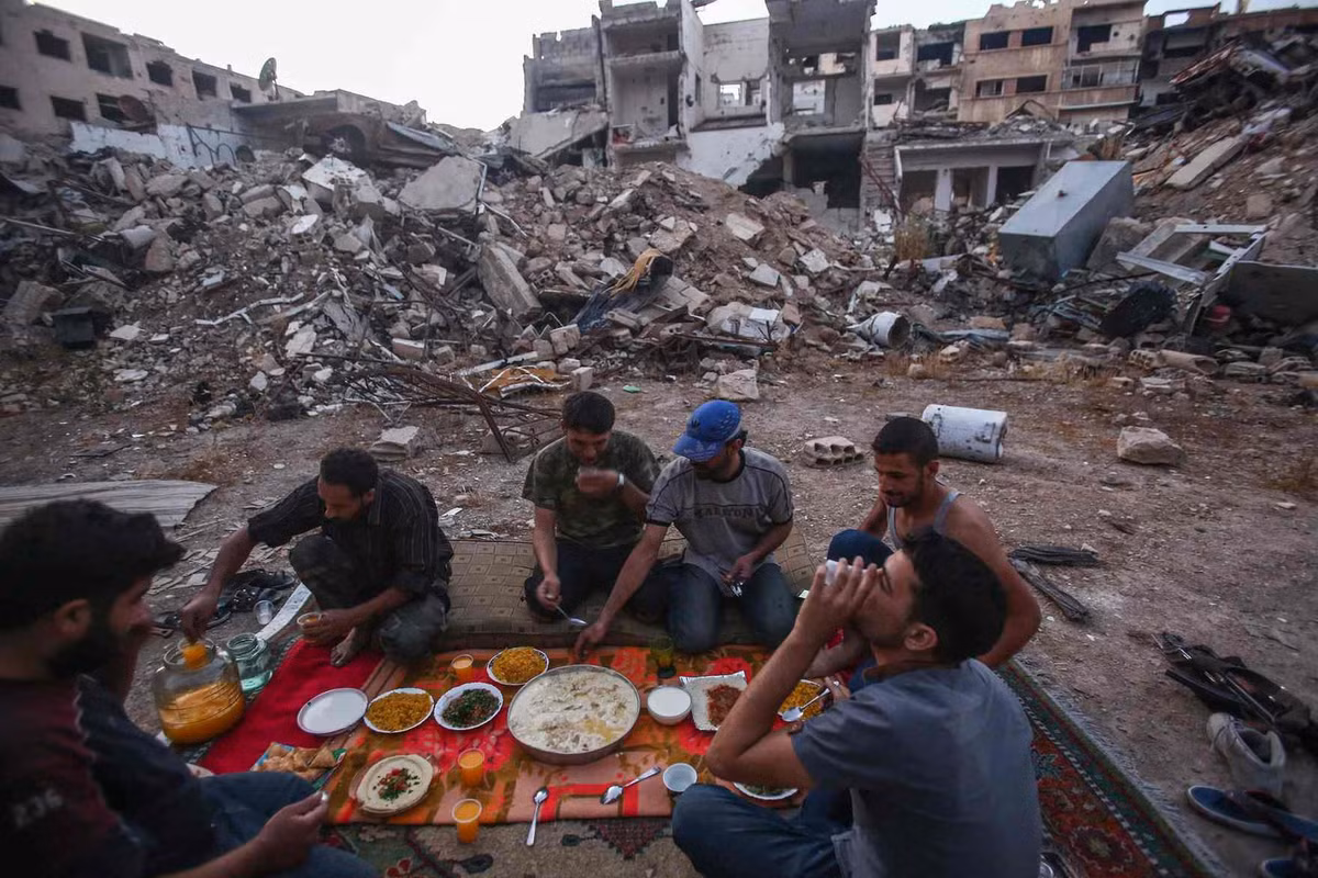 Trong ảnh, các binh sĩ quân đội Syria tự do (FSA) tập trung ăn uống vào bữa sáng trong tháng ăn chay Ramadan giữa khung cảnh hoang tàn.