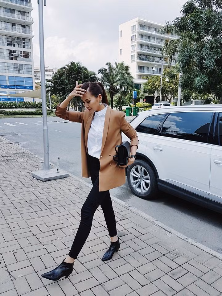 Áo vest dáng dài màu be kết hợp đơn giản với áo sơ mi trắng cùng với skinny và chiếc bóp cầm tay tối màu mang lại vẻ thanh lịch, sang trọng cho siêu mẫu Thanh Hằng. Ảnh: xaluan.com.vn.