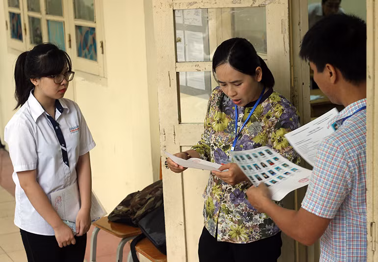 Cán bộ coi thi đọc tên thí sinh vào phòng thi và kiểm tra thông tin lại lần nữa một cách chính xác.
