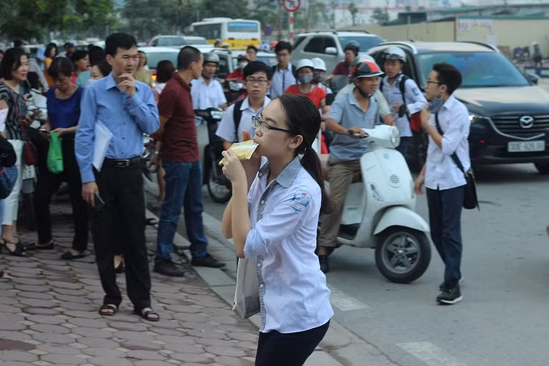 Một nữ sinh xinh xắn vừa uống vội ít sữa tươi, vừa chạy vội vào phòng thi.