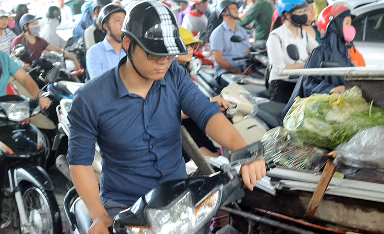 Một nam thanh niên cố gắng len lỏi qua các xe khác để tìm đường di chuyển.