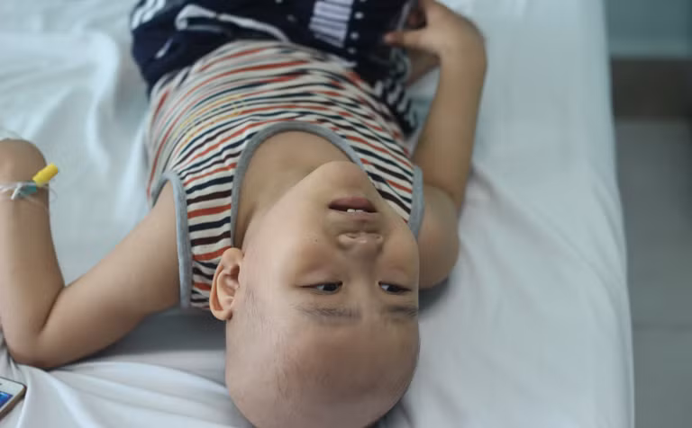 Nằm trên giường bệnh, thỉnh thoảng cháu Phong (6 tuổi, quê Ân Thi, Hưng Yên) lại khóc mếu máo, chỉ đòi bà nội cho về nhà. "Cháu về được mấy hôm lại lên truyền hóa chất. Nếu lúc nào nhanh nhất thì hai ba tuần về nhà một lần, còn chậm thì năm sáu tuần. Cháu điều trị tại đây có bảo hiểm nên bớt được phần nào chi phí, nhưng việc đi lại xa xôi, vất vả lắm chú ạ. Tết thiếu nhi cũng chả mua được gì cho cháu, thỉnh thoảng chỉ ngồi pha trò cho cháu cười, khỏi khóc thôi", người thân cháu Phong chia sẻ.