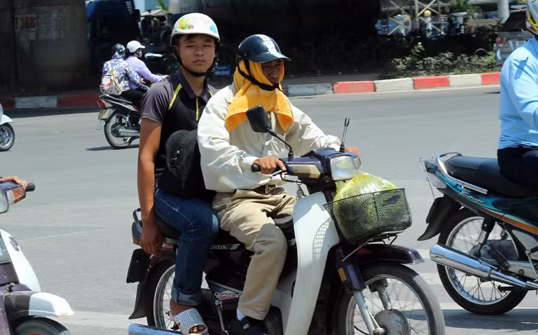 Một số xe ôm phải sử dụng khăn mặt thấm nước trùm lên đầu rồi đội mũ bảo hiểm để giảm bớt nhiệt độ nắng nóng.