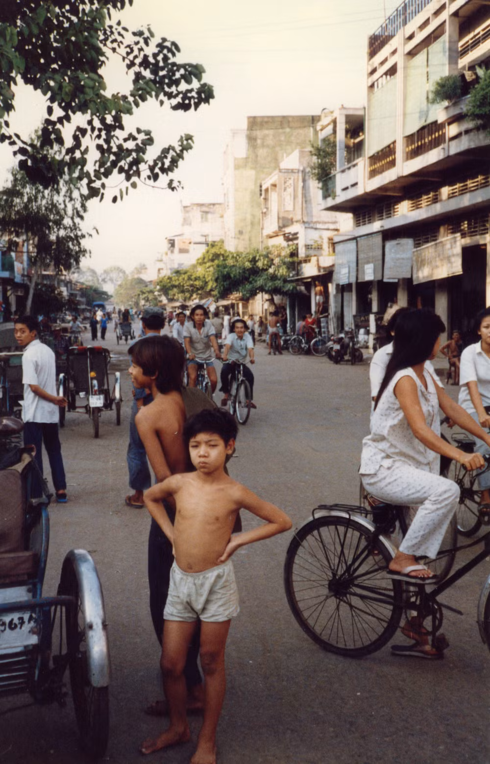 Chú bé đứng chống nạnh trên con phố đông.