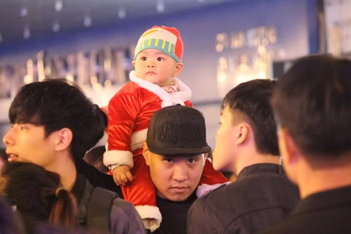 Bé trai được cha mẹ khoác bộ đồ ông già Noel đi chơi Giáng sinh.