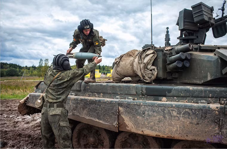 Hai thành viên kíp lái tăng T-90A đang vận chuyển các quả đạn 125mm lên xe.