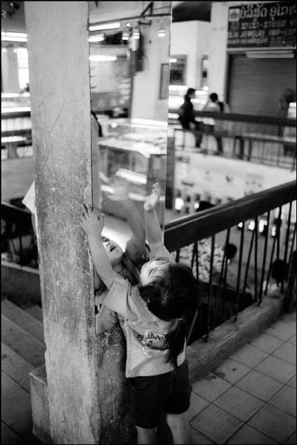 Em bé chơi đùa với tâm gương ở chợ trung tâm, 8/3/1998. Ảnh: John Vink / Magnum Photos.