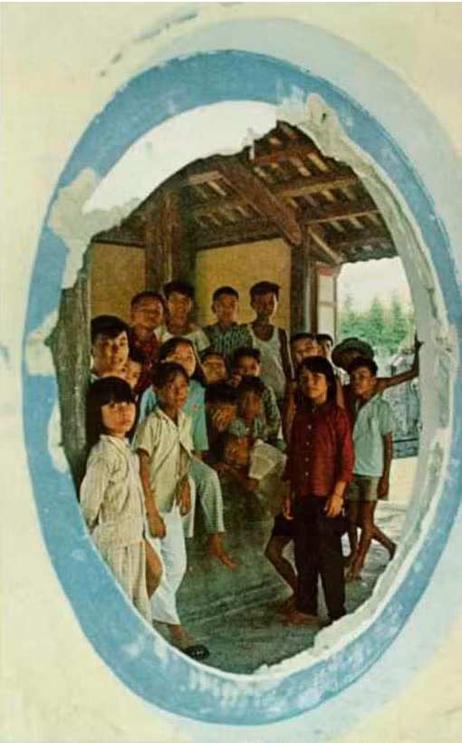 Những đứa trẻ trong Bi Đình của lăng vua Tự Đức, nhìn qua cửa sổ tròn đã bị bom đạn phá vỡ của công trình này. Ảnh: National Geographic.