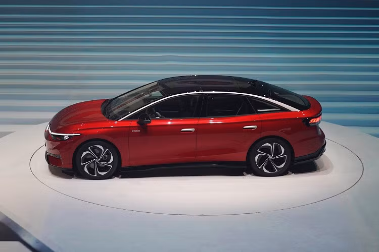 Tương tự các mẫu xe điện ID khác của Volkswagen, ID.7 cũng được áp dụng phong cách thiết kế tối giản. Trên đầu xe, mẫu ô tô điện này có điểm nhấn đáng chú ý nhất là dải đèn LED định vị ban ngày nằm vắt ngang, nối với logo phát sáng của hãng Volkswagen. Thêm vào đó là cụm đèn pha LED gọn gàng, vuốt mượt mà về phía sau và hốc gió trung tâm nối liền với khe gió ở hai góc cản trước.