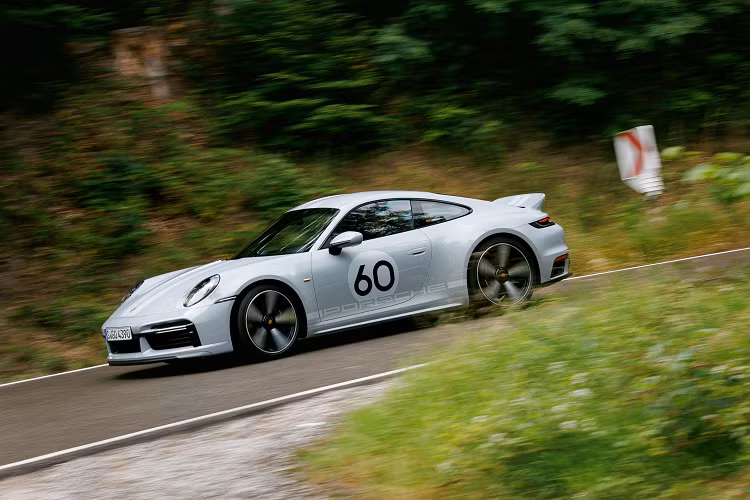 Logo Porsche màu trắng bên cửa và sẽ có sự xuất hiện ngẫu nhiên hoặc khách tự lựa con số từ 1 đến 99 cho phù hợp với mình, la-zăng Fuchs 5 chấu đơn dạng phay xước khá cổ điển, phần mui của xe 911 Sport Classic 2023 được làm từ nhựa gia cố sợi carbon (CFRP) hay cánh gió sau kiểu "đuôi vịt" lấy cảm hứng từ chiếc Carrera 2.7 RS 1973.