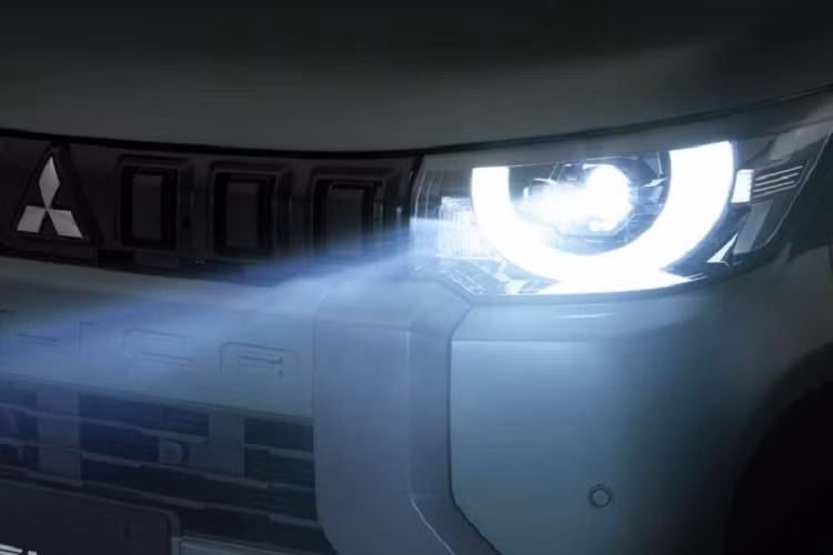 Phía dưới là dòng chữ "Delica" được dập chìm và lưới tản nhiệt bao quanh bằng nẹp dày dặn, tích hợp đèn sương mù trước. Trong khi đó, cản trước được sơn màu đen với hốc gió trung tâm và ốp màu bạc tạo cảm giác rắn rỏi cho khu vực đầu xe.