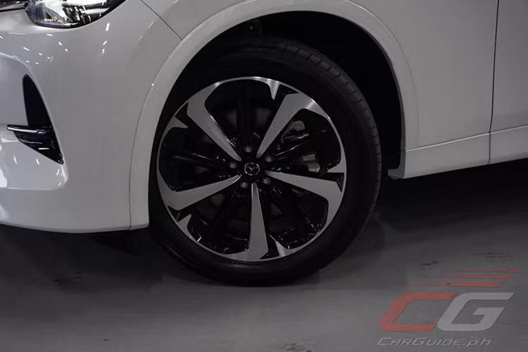 Thay vì những điểm nhấn sáng bóng trên xe, gói Premium Sport lại mang đến viền lưới tản nhiệt và nẹp trang trí màu đen trên chắn bùn trước. Ngoài ra, với gói Premium Sport, Mazda CX-60 2024 còn được trang bị những chi tiết mạ crôm màu tối trên lưới tản nhiệt, bộ vành hợp kim 20 inch.