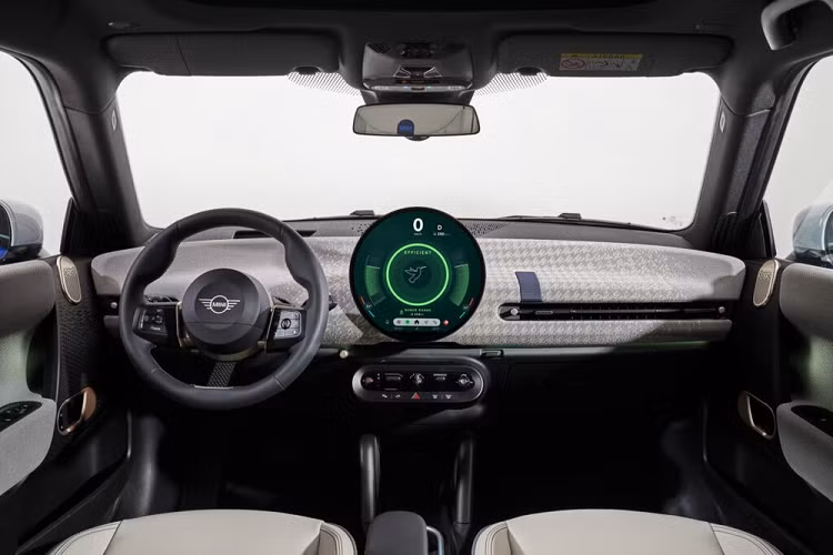 Bên trong xe, Mini Cooper Electric 2024 cũng được trang bị màn hình cảm ứng OLED 9,4 inch hình tròn nằm giữa mặt táp-lô, đóng vai trò bảng đồng hồ và màn hình giải trí. Được gọi bằng cái tên Mini Interaction Unit, màn hình này chạy bằng hệ điều hành Mini Operating System 9. Phần lớn các tính năng của xe đều được chỉnh qua màn hình này.