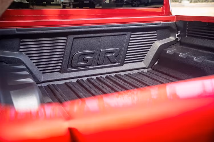 Bên trong Toyota Hilux GR Sport 2023 là không gian nội thất có màu đen chủ đạo. Tất nhiên, xe vẫn có những điểm nhấn như bộ bàn đạp thể thao bằng kim loại và dây đai an toàn màu đỏ. Phía sau vô lăng còn có thêm lẫy chuyển số thể thao.