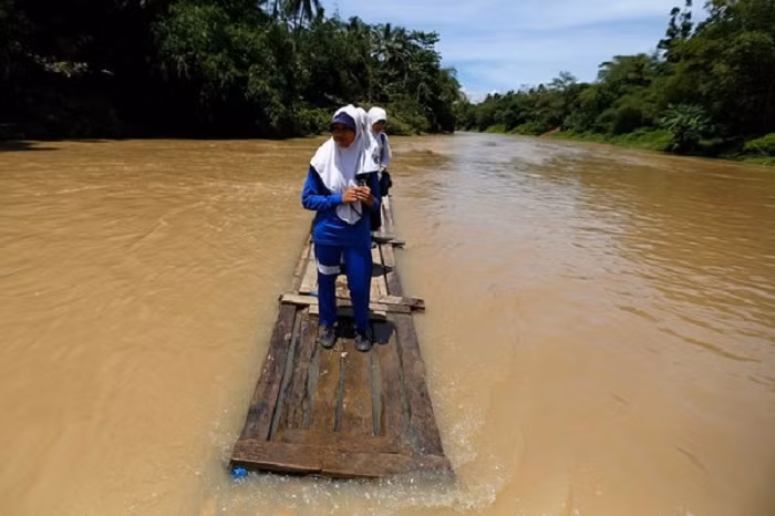 Trẻ em sống ở Cilangkap, Indonesia phải đến trường trên những ‘chiếc thuyền’ tạm bợ khi chiếc cầu duy nhất bắc qua sông Ciherang bị lũ cuốn trôi.