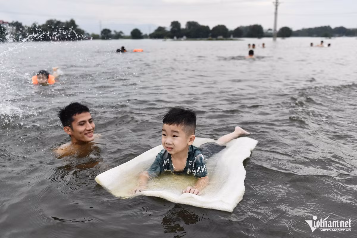 Bé Công Phúc được người lớn đưa ra đây tập bơi với miếng xốp đủ để đỡ trọng lượng cơ thể. "Vừa để bé nghịch nước mát vừa để dạy bé làm quen với bơi lội, vì khu vực này gần sông, hằng năm thường xuyên bị ngập lụt", người thân của bé chia sẻ.