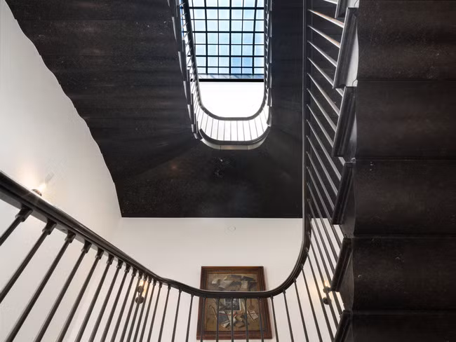 Cầu thang bằng đá cẩm thạch đen dẫn lên tầng trên với phòng ngủ chính của căn penthouse.