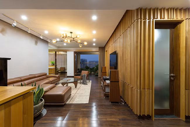 Phòng khách trước đây thiếu ánh sáng, ảm đạm nay đã trở nên rực rỡ, sáng sủa với một bức tường gỗ thơm vừa mang tính chất trang trí vừa cách âm hiệu quả.