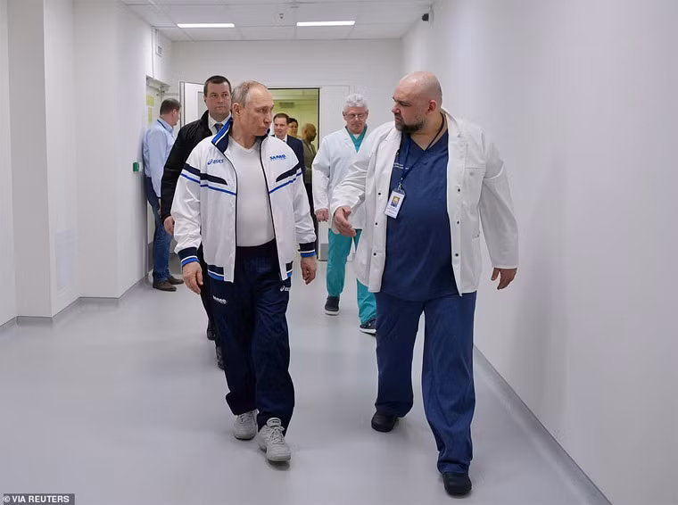 Ông Putin chụp ảnh cùng với bác sĩ trưởng của Bệnh viện Komunarka, Denis Protsenko. “Tôi quan sát họ làm việc. Tất cả các nhân viên y tế đang ở vị trí chiến đấu. Tôi không muốn dùng những sự diễn đạt mang tính chất quân sự này nhưng thực sự mọi thứ đang được tiến hành như một bộ máy khổng lồ” – Tổng thống Putin nói.