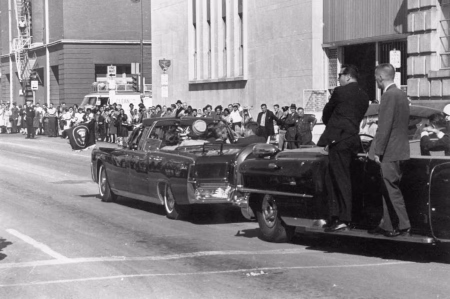Vào thời điểm bị ám sát, Tổng thống Kennedy ngồi trên chiếc limousine mui trần cùng với vợ - Đệ nhất phu nhân Jacqueline. Lee Harvey Oswald, cựu lính hải quân, ẩn nấp tại cửa sổ tầng 6 trong một tòa nhà gần nơi đoàn xe của Tổng thống Kennedy đi qua rồi bóp cò súng 3 lần.