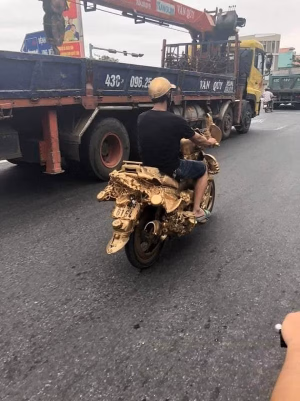 Đáng chú ý, anh chàng độ xe máy còn sơn một màu vàng óng trông không khác gì được hoá cho "các cụ" nhân ngày rằm, mùng 1. Lo sợ không ăn rơ, chàng trai này còn sơn chiếc mũ bảo hiểm cùng màu với chiếc xe trông hết sức kì cục.
