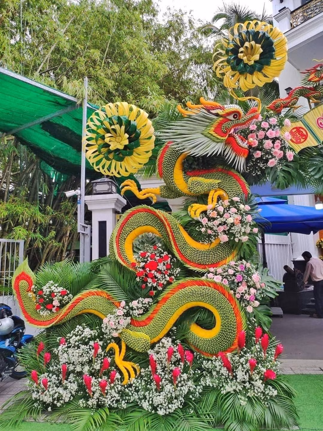 Nguyên liệu chính của chiếc cổng là lá dừa, kết hợp cùng với tre, hoa đã tạo nên thành phẩm ai đi qua cũng phải ngoái nhìn.