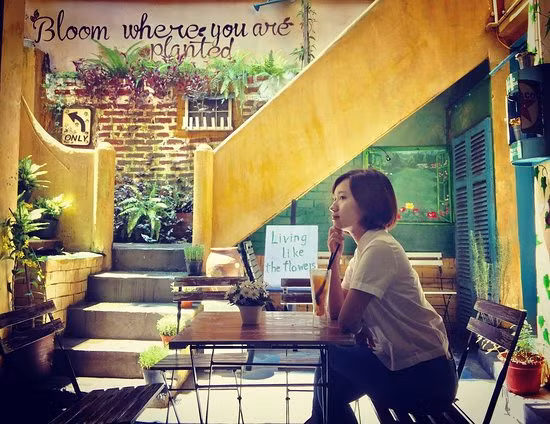 Ngay dưới chân cầu thang, chủ quán cũng tinh ý đặt chiếc bàn nhỏ xinh bên cạnh bức tường vàng phủ rêu.