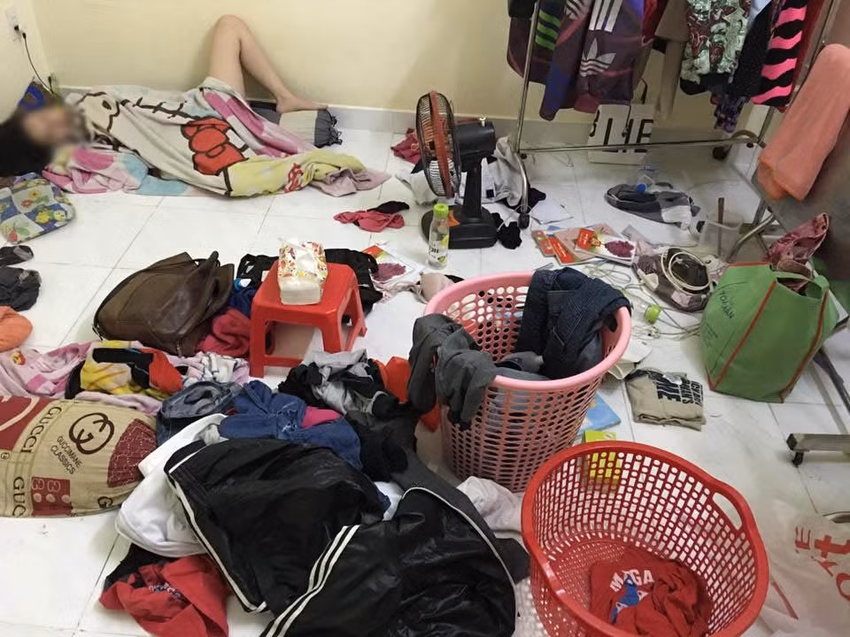 Căn phòng bừa bộn áo quần, đồ ăn, vật dụng, còn cô gái thì nằm vào 1 góc.