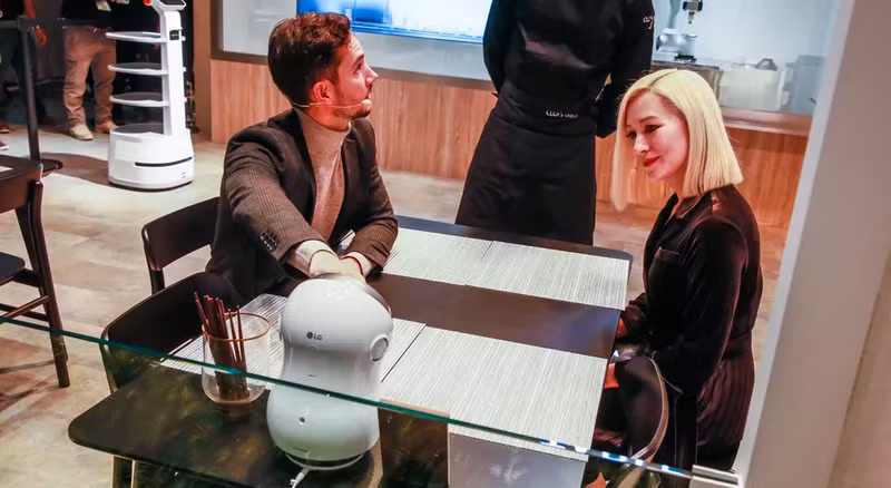 Nhân viên giải thích cho khách cách họ có thể tương tác với robot trên bàn.