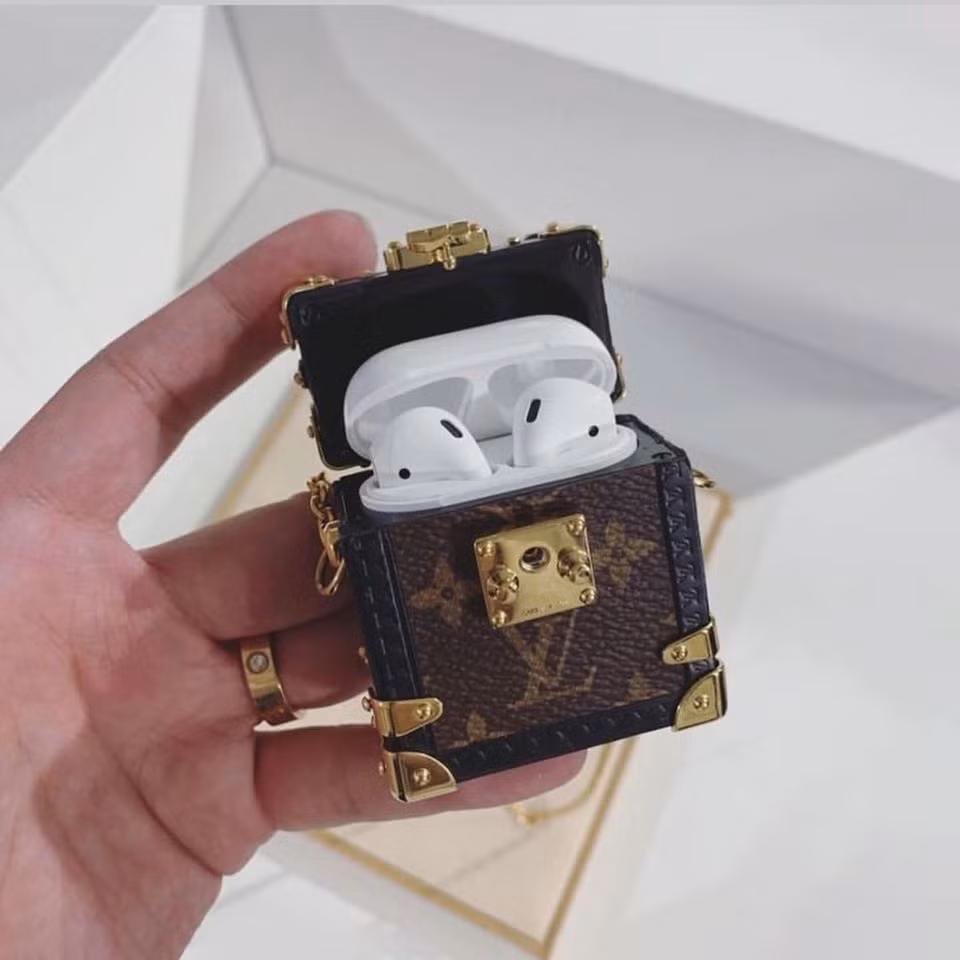 2. Louis Vuitton Thiết kế hộp đựng như một chiếc rương (trunk) thu nhỏ bao phủ chất liệu da với họa tiết monogram đặc trưng của LV. Đặc biệt phần dây đeo mắt xích tông vàng có thể đeo ở cổ hay trên vai như một phụ kiện thời trang. Hộp đựng AirPods đến từ Louis Vuitton có giá bán niêm yết 995 USD.